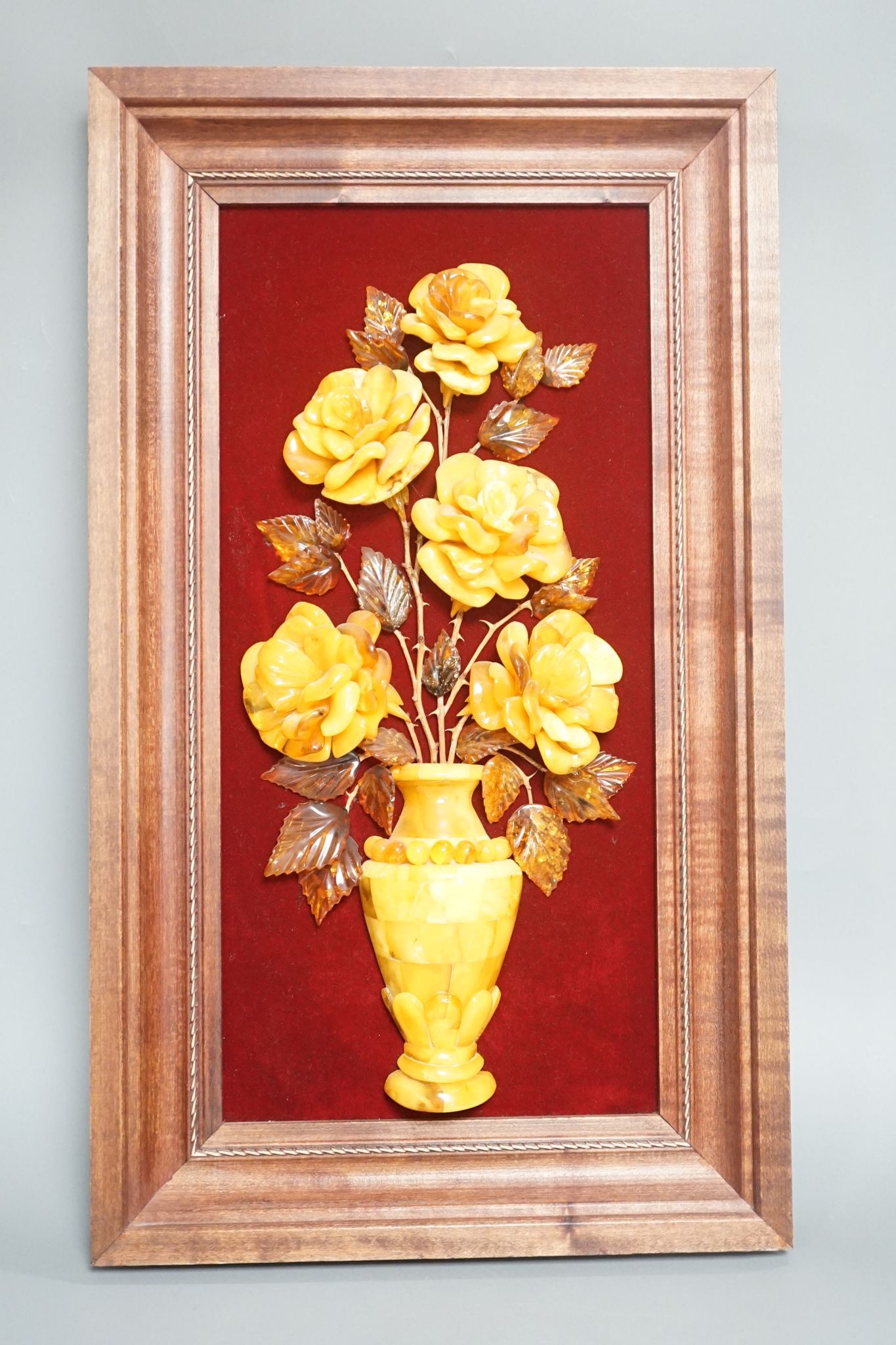 A carved amber panel from the Hermitage Museum shop, St Petersburg, roses in a vase. 49x39cm including frame